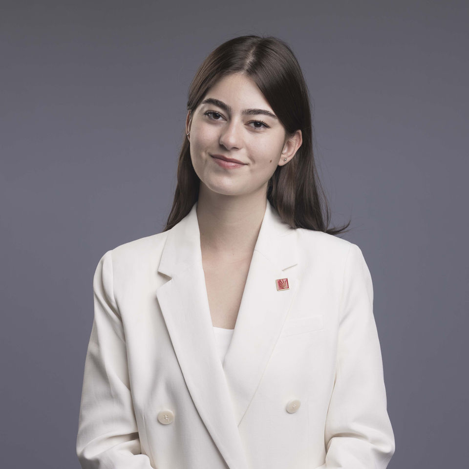 Young woman in white blazer smiling; a professional portrait.