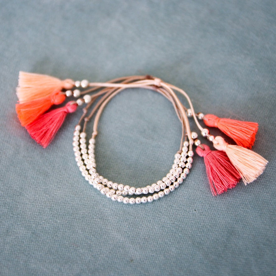 Thumbnail: Handmade silver bead bracelet with coral and blush cotton tassels.