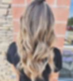 Long blonde balayage hair with wavy styling.