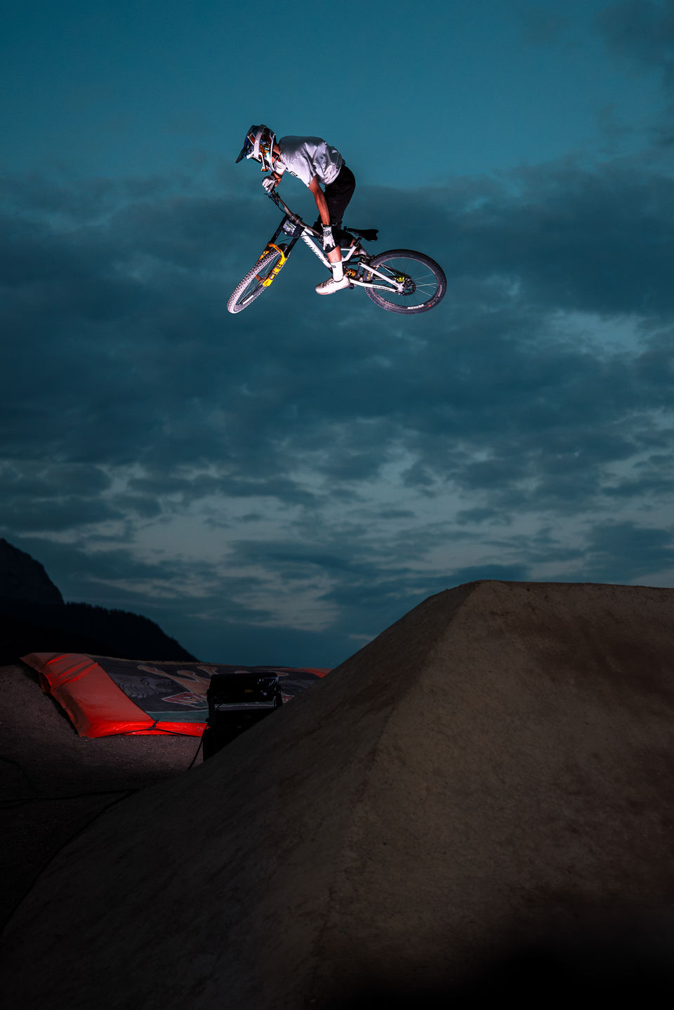 Mountainbiker springt bei Nacht über eine Schanze