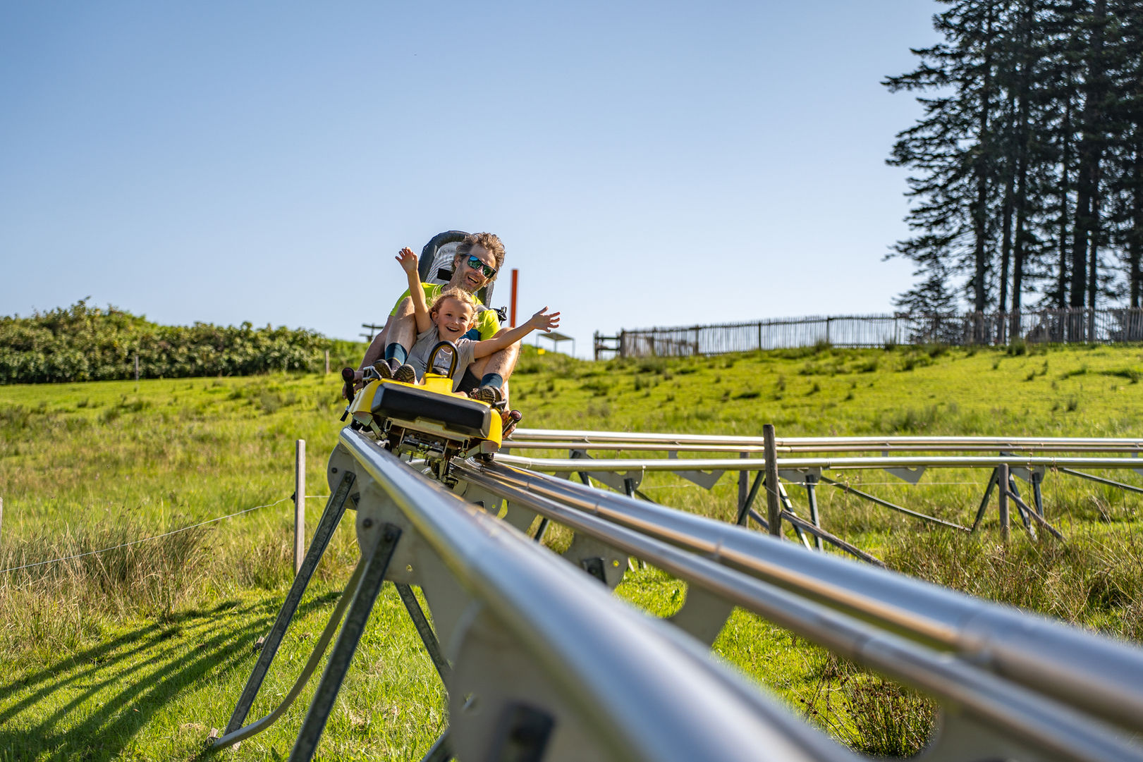 Vater und Kind fahren mit einer Sommerrodelbahn