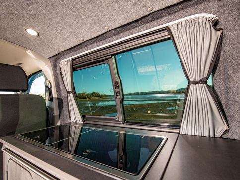 Silver grey curtains tie back behind kitchen area in campervan conversion silver carpet