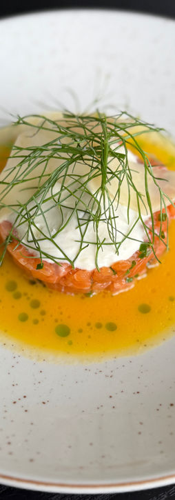 Un plato que presenta un filete de salmón junto a una guarnición de verduras verdes.