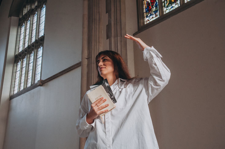 Aliona standing in a church with a Bible, her thoughts filled with memories of her late mother and the solace found in faith.