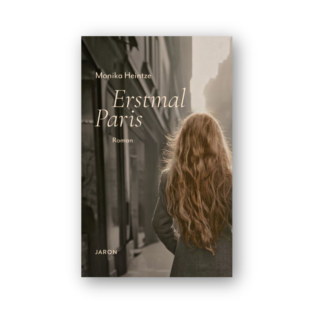 Eine junge Frau mit langen Haaren geht an einer Hausfassade vorbei