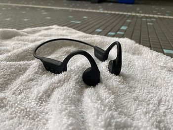 Waterproof swim headphones sitting on a towel at the edge of a pool