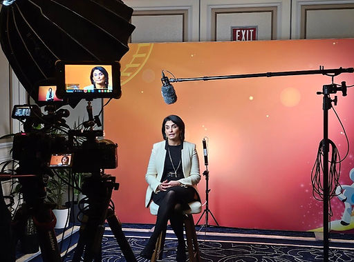 Seema Verma sitting on a stool in front of a camera at a Hlth interview