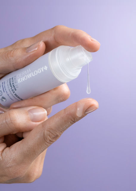 Styled product shoot with skincare bottles and a hand model