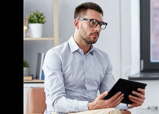 A man in glasses looks at a tablet, symbolizing the Mental Health Partial Care Program in