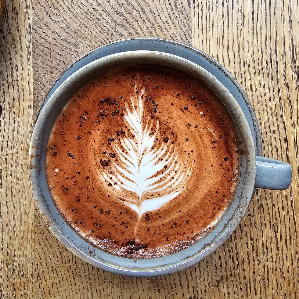 Close-up view of a barista preparing a latte with latte art in a small town cafe