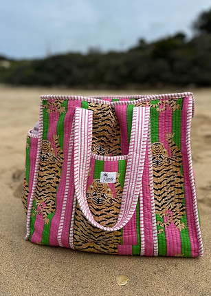 Pink striped tiger print quilted tote bag, on beach background.