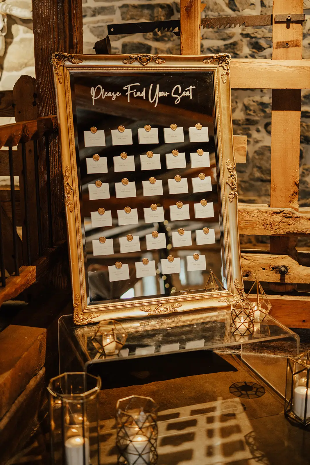 Elegant wooden seating chart display with white escort cards and greenery for a cohesive wedding signage suite at the barn at silverstone luxury wedding venue.