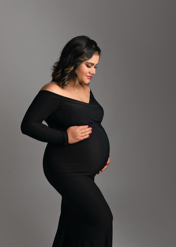Our black silhouette dress is ever-popular and showcases her beautiful baby bump in this quiet moment thinking about baby, portrait by Christchurch maternity, newborn and baby photographer Kirsten Naomi Photography