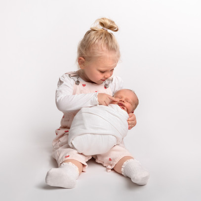 Toddler playing a game of “find the nose” with her newborn baby brother, photo by Christchurch Newborn Photographer Kirsten Naomi Photography