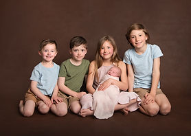 Four proud siblings cuddle their newborn sister by Christchurch Newborn Photographer Kirsten Naomi Photography