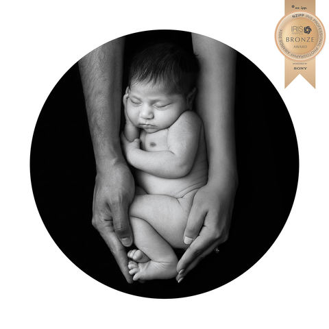 Newborn Baby Portrait featuring a Newborn baby cradled in her parent’s arms that received a Bronze Award in the NZIPP Iris Awards, photograph by Christchurch Maternity, Newborn and Family Photographer Kirsten Naomi Photography