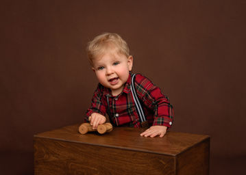 Smiling baby boy playing with a wooden toy car, photograph by Christchurch Baby Photographer Kirsten Naomi Photography