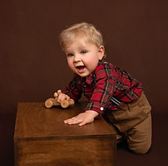 Smiling baby boy playing with a wooden toy car, photograph by Christchurch Baby Photographer Kirsten Naomi Photography