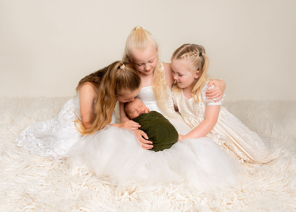 Three sisters kissing and cuddling their newborn baby brother, photo by Christchurch Newborn Photographer Kirsten Naomi Photography