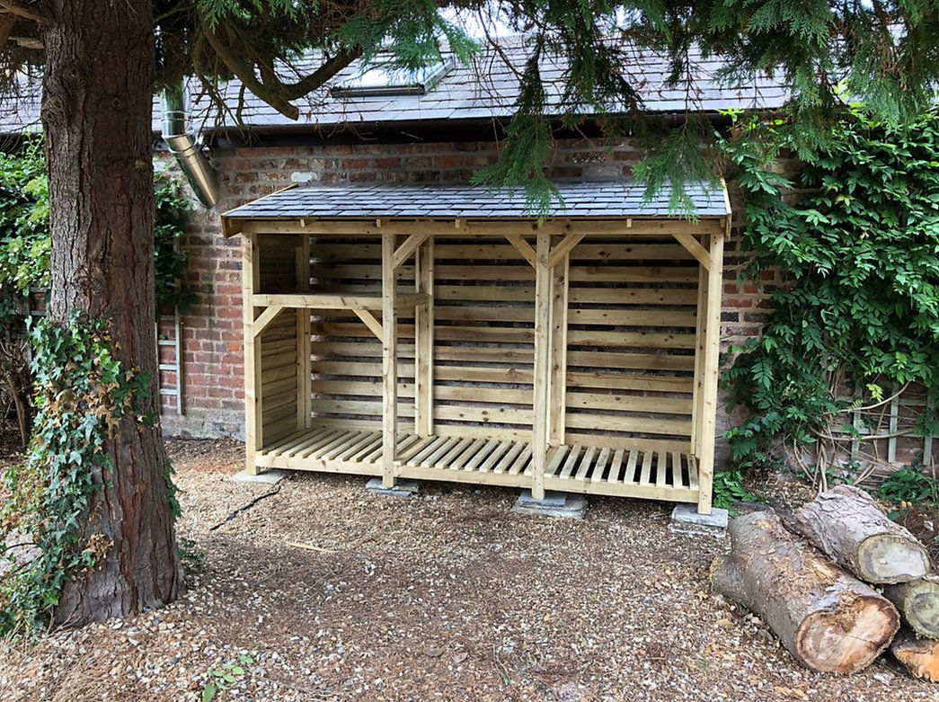 Handmade three-bay log store with a kindling shelf empty view