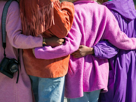 women embracing each other with their backs facing the camera
