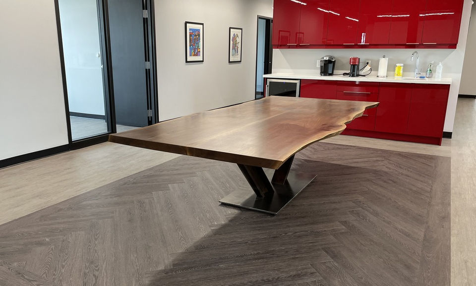 Live edge walnut dining table with V-shaped steel base in modern kitchen and dining space.
