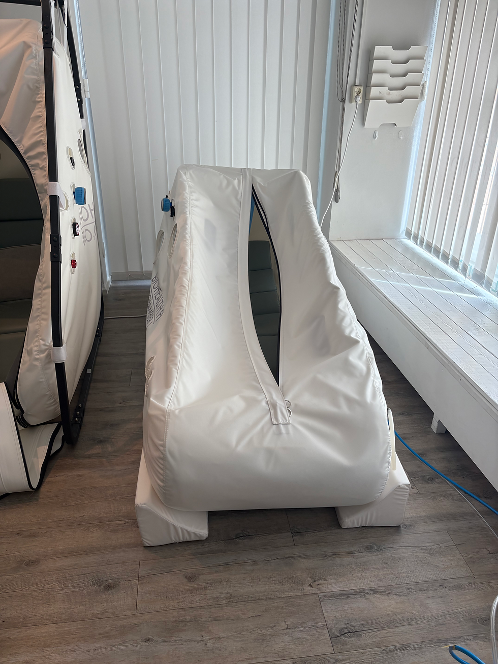 Two white inflatable sauna or recovery pods in a bright room with vertical blinds, wood floor, and wall-mounted organizer.