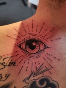Tatouage d’œil rayonnant sur l’épaule, avec effets de lumière en ligne fine. Symbole de perception et de spiritualité, réalisé par L'Ink Tattoo à Quissac (30260).