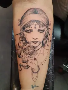 Tatouage de femme pirate ou gitane avec serpent, expression réaliste, ligne fine et composition narrative. Œuvre sur le bras signée L'Ink Tattoo.