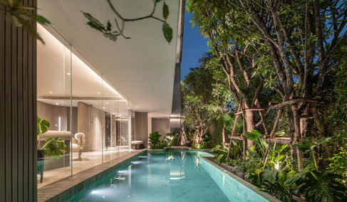 Night pool view with trees providing privacy and green buffer at Kalm Ari Bangkok.