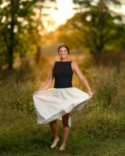 Senior girl twirling in a white skirt during golden hour