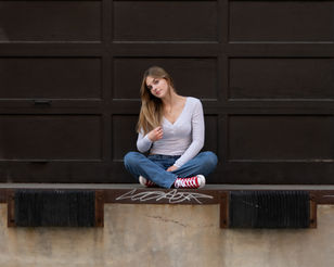 Senior girl sitting cross-legged on an urban loading dock