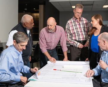 Professional team reviewing architectural blueprints in an office setting.