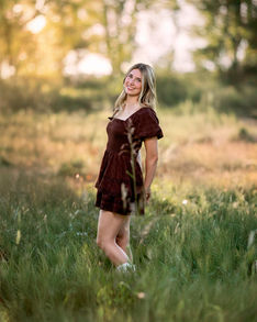 Smiling girl in brown dress during golden hour field portrait.