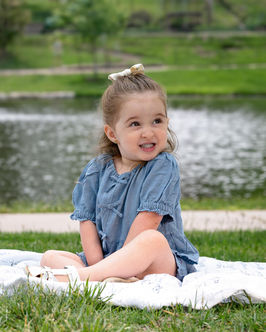 Young girl in a blue dress for family portraits by a pond