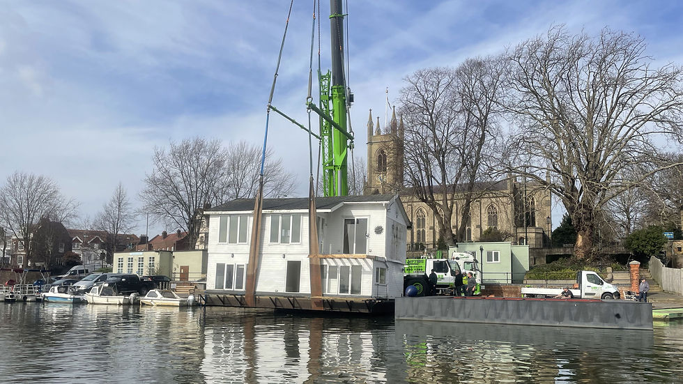 The houseboat being craned out and lifted onto its new hull
