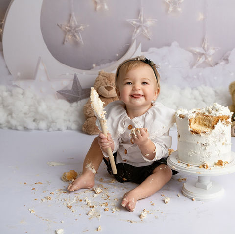 baby girl having fun whilst smashing her cake for her first birthday portraits taken by photographer near peterborough