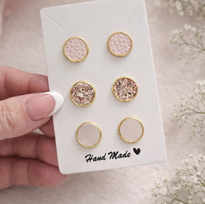 Handmade eco stud earrings in blush and glitter faux leather displayed on a branded card
