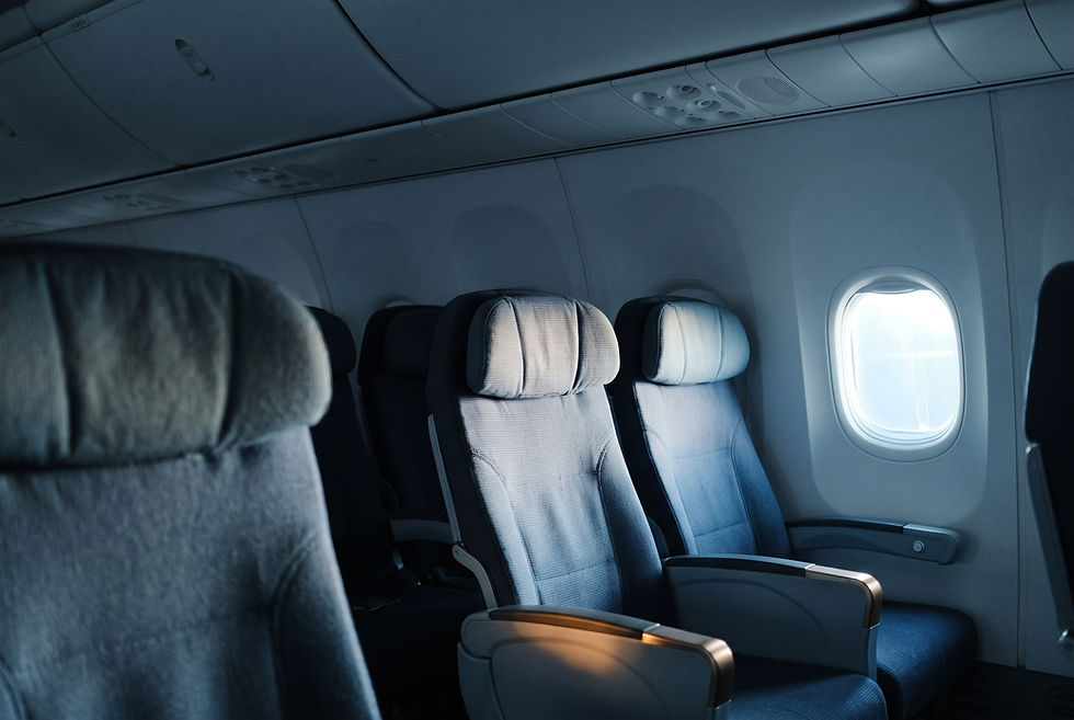 Empty airline seat row beside a window at cruising altitude, with cool blue light entering the cabin