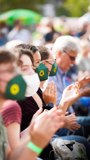 Zuschauer klatschen, einige mit grünen Masken