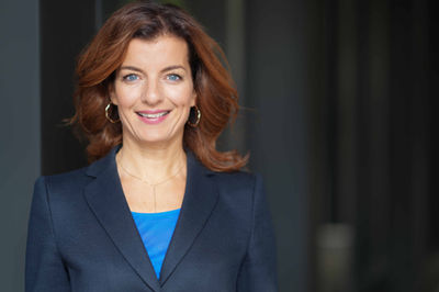 Outdoor C-level Headshot einer Frau vor dunklem Hintergrund
