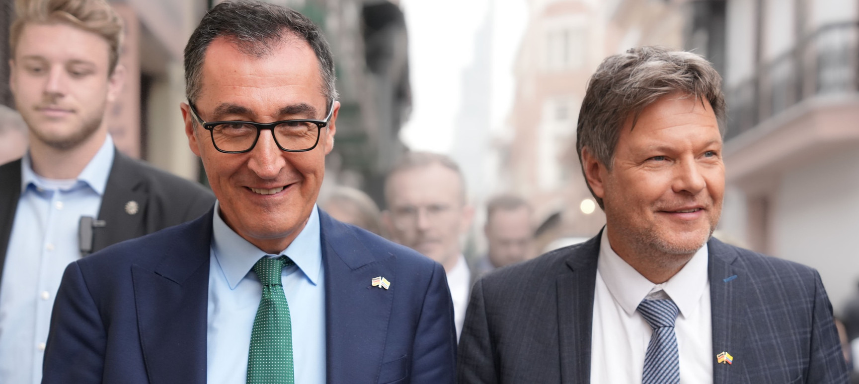 Cem Özdemir und Robert Habeck laufen fröhlich auf der Straße.