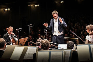 Eventfoto: Ein Dirigent dirigiert emotionianal sein Orchester