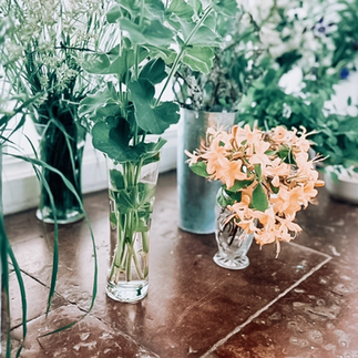 Blommor och växter i vaser på stengolv.