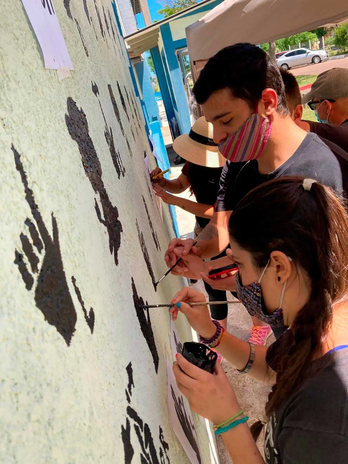 Personas en situación de discapacidad pintando un muro blanco
