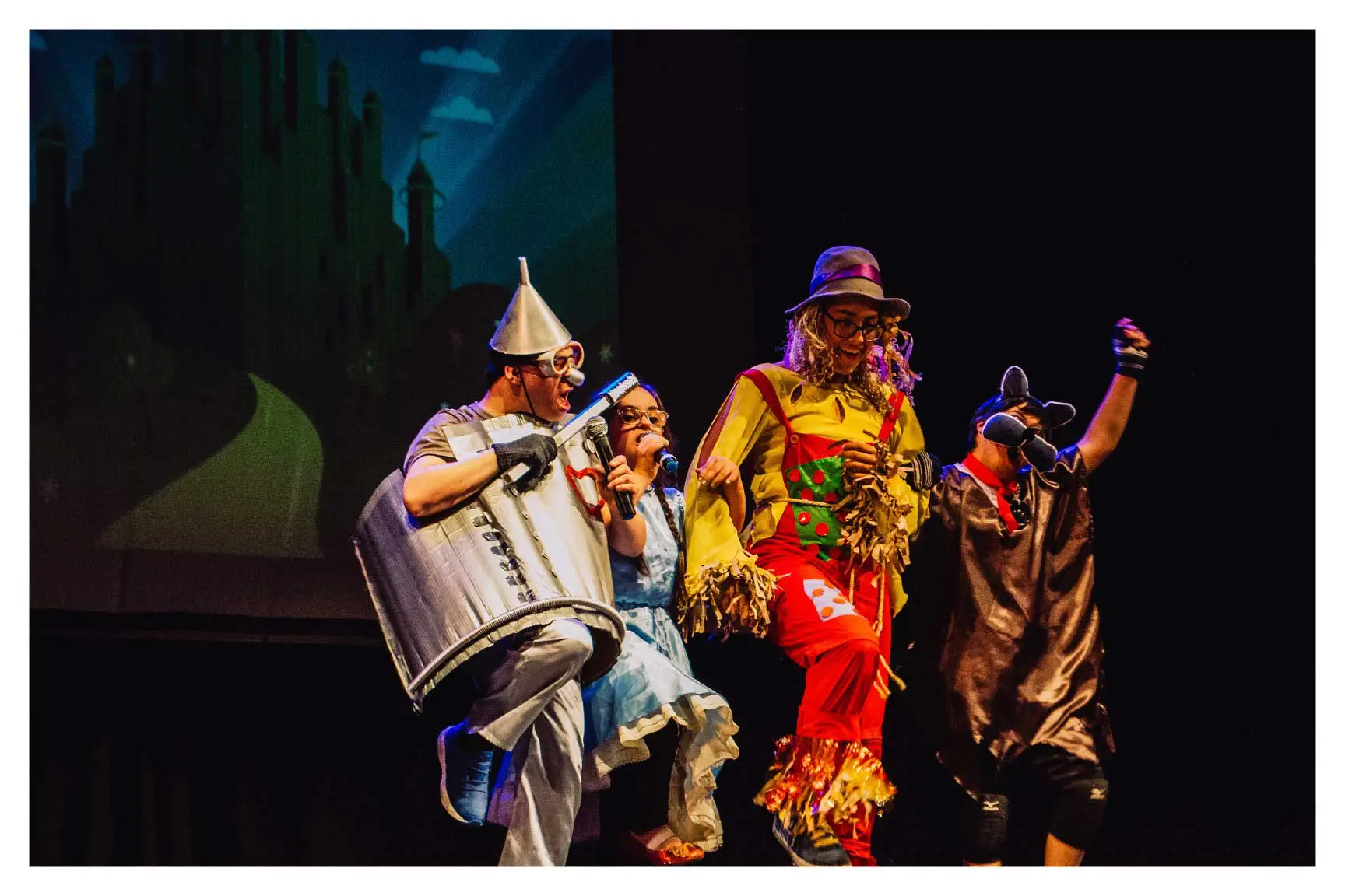 Estudiantes con discapacidad bailando sobre un escenario y vestidos con trajes del musical "El mago de Oz"