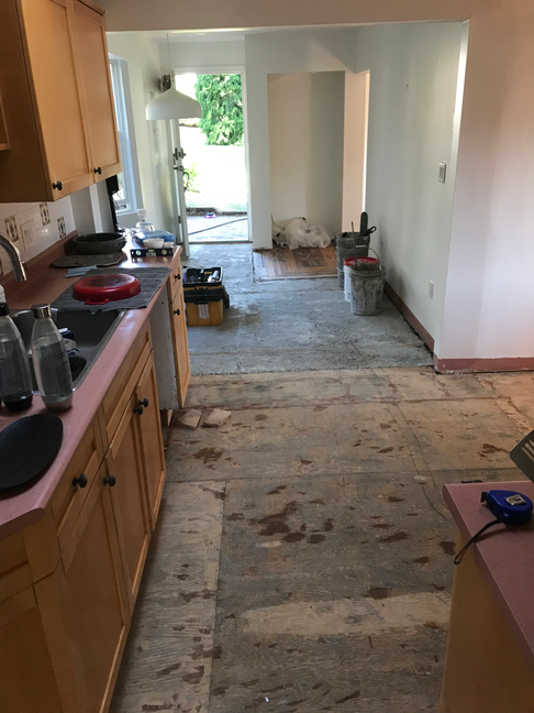 Kitchen hallway before flooring installation, with old flooring removed and subfloor exposed.