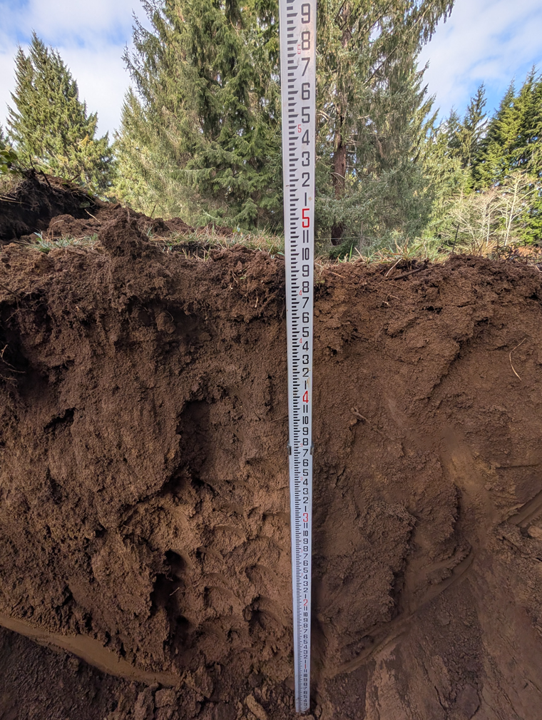 Photo of a soil test pit for evaluation to determine the soil type, structure, texture and depth for septic system design.