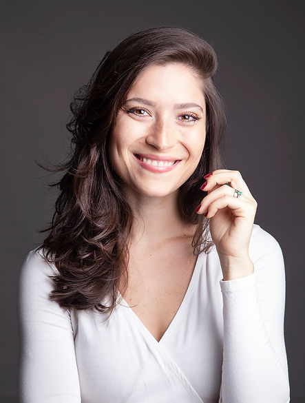 Giovanna Biondi, mulher sorrindo, cabelos castanhos médios, pele clara e camiseta branca.