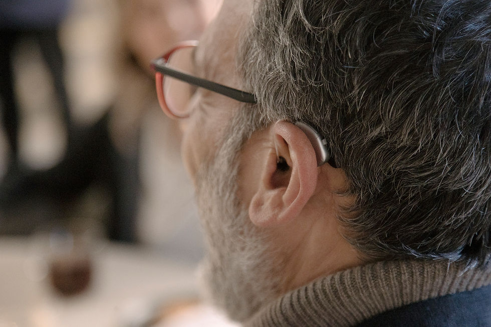 Hombre mayor usando aparato auditivo detrás de la oreja, mostrando solución auditiva para controlar síntomas de tinnitus